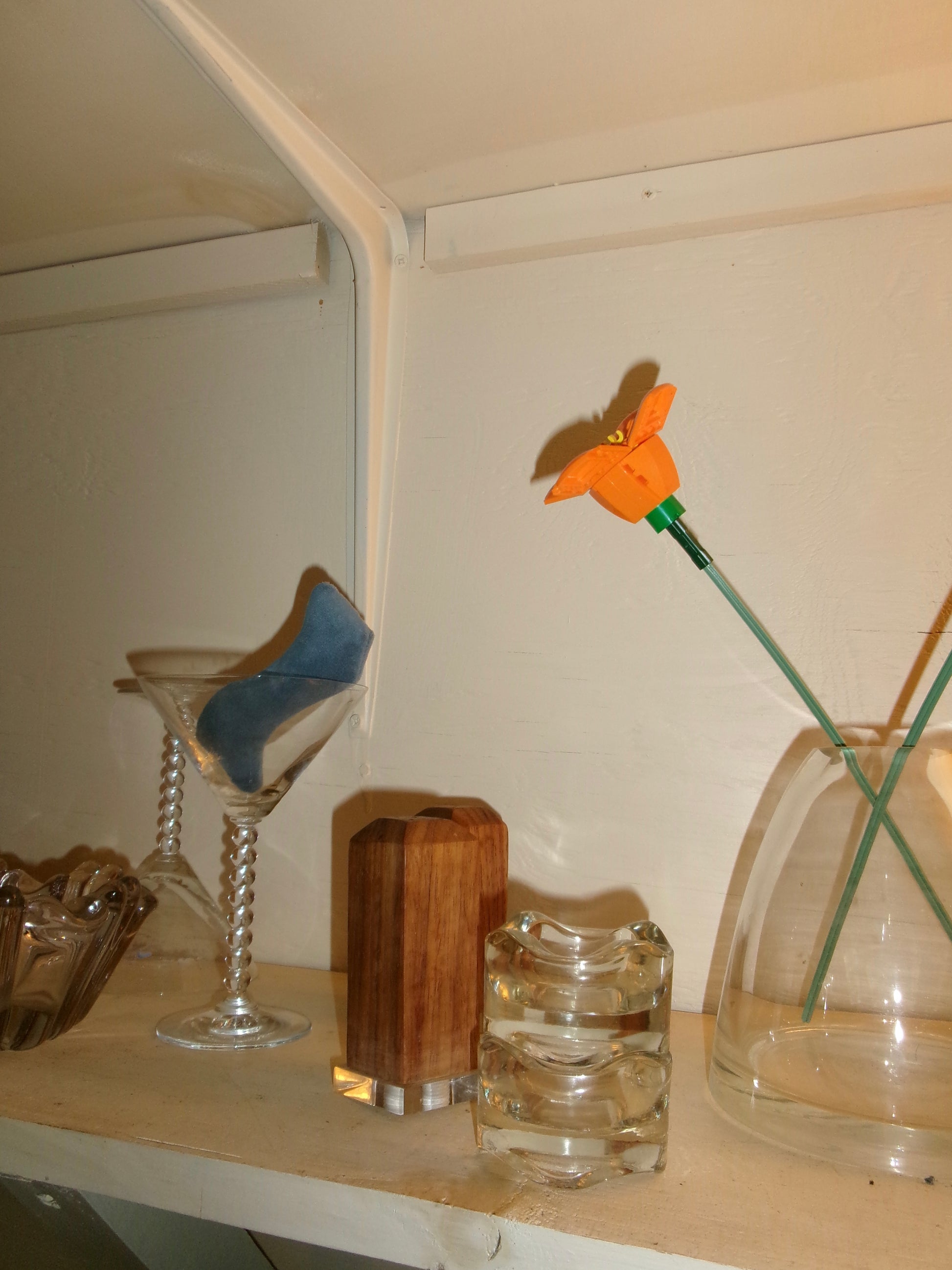 Glass vase on a shelf with other hombre items in the collection: all displaying similar elements like glass, wood, and pops of color.